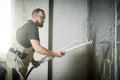 Plasterer using screeder spraying putty plaster mortar on wall Royalty Free Stock Photo