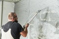 Plasterer using screeder spraying putty plaster mortar on wall Royalty Free Stock Photo