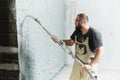 Plasterer using screeder spraying putty plaster mortar on wall Royalty Free Stock Photo