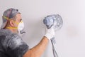 Plasterer wearing dust mask polishes a wall with sanding machine