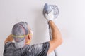 Plasterer wearing dust mask polishes a wall with sanding machine Royalty Free Stock Photo