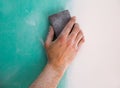 Plastering man hand sanding the plaste in drywall seam