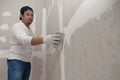 Plasterwork and wall painting preparation. Asian male applying filling drywall patch