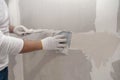 Plasterwork and wall painting preparation. Asian male applying filling drywall patch