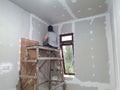 Plasterwork and wall painting preparation. Asian male applying plaster or filling drywall patch