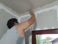 Plasterwork and wall painting preparation. Asian male applying plaster or filling drywall patch