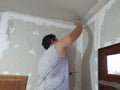 Plasterwork and wall painting preparation. Asian male applying plaster or filling drywall patch