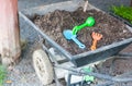 Plastic agriculture tools like harrow and shovel put in black soil in metal cart ready to used for kid learning