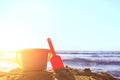 Plastic baby pink bucket with a shovel on the sand on the beach by the sea on a sunny day with copy space Royalty Free Stock Photo