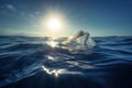 plastic bag floating on the surface of the ocean, with sun shining down Royalty Free Stock Photo