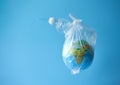 A plastic bag with a globe and a plastic bottle on a blue background. Concept: planetary plastic pollution