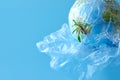 A plastic bag with a globe and a plastic bottle on a blue background. Concept: planetary plastic pollution