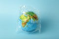 Plastic bag pollution concept. Earth globe in a plastic bag on a colored background. Plastic and waste pollution oceans, nature Royalty Free Stock Photo