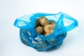 Plastic bag with potatoes on a white background. Blue package with potatoes on a light background. Royalty Free Stock Photo