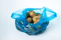 Plastic bag with potatoes on a white background. Blue package with potatoes on a light background. Royalty Free Stock Photo