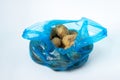 Plastic bag with potatoes on a white background. Blue package with potatoes on a light background. Royalty Free Stock Photo