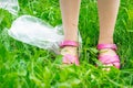 Plastic bags trash with children`s feet on green grass