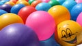 Smiling rubber ball among unprinted plastic balls