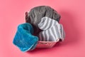 Plastic basket for washing full of different clothes striped socks, underpants, towel lies on pink countertop in laundry Royalty Free Stock Photo