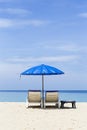 Plastic beach bench under blue umbrella over blue sea view Royalty Free Stock Photo