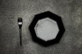 Plastic black fork and Empty ceramic black octagon polygon shape plate on grunge leather background