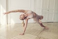 plastic blonde with a good stretch showing yoga asanas in a room by the window