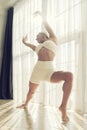 plastic blonde with a good stretch showing yoga asanas in a room by the window