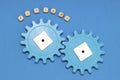 Plastic blue gears on a blue background, the word process. The concept of interaction, process. The photo