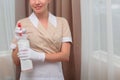 A plastic bottle of air freshener in the hands of a maid. Hands in white cotton gloves. An unrecognizable photo of the interior.