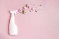 Plastic bottle with cleaning spray and flowers on pink background. Royalty Free Stock Photo