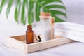 Plastic bottle filled with white bath sea salt and wooden spoon, amber color dropper and white towels on wooden tray Royalty Free Stock Photo