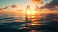 Plastic bottle floating in ocean at sunset, glowing sunlight and clouds. Environmental pollution and conservation Royalty Free Stock Photo