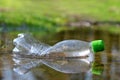 Plastic bottle floating in puddle of water. Pollution garbage in forest.