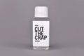 Plastic bottle with made up label saying ` 45ml Cut the crap Serum` on gray background