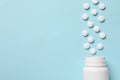 Plastic bottle with many white pills on light blue background, flat lay. Space for text Royalty Free Stock Photo
