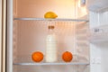 Bottle of milk and  set of fruit in empty refrigerator Royalty Free Stock Photo