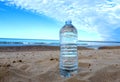 Plastic bottle with mineral water on beach by sea. PET bottle on the sand. Royalty Free Stock Photo