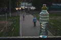 Plastic bottle top full with water with yellow cap in a park or garden with green trees in blurred background Recyclable beverage Royalty Free Stock Photo