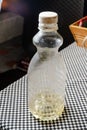 Plastic bottle with yellow liquid on checkered tablecloth near basket and dark background Royalty Free Stock Photo