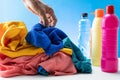 Plastic bottles of cleaning products with pile colorful clothes on table background Royalty Free Stock Photo