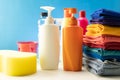 Plastic bottles of cleaning products with pile colorful clothes on table background Royalty Free Stock Photo