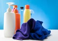 Plastic bottles of cleaning products set with pile clothes on white table background Royalty Free Stock Photo