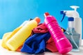 Plastic bottles of cleaning products set with pile clothes on white table blue background Royalty Free Stock Photo