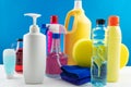 Plastic bottles of cleaning products set with pile clothes on white table blue background Royalty Free Stock Photo