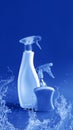 Plastic bottles with cleaning products and sponge on blue water drops background. Mockup, place for your label