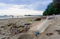 Plastic bottles left on the dirty sand beach with various garbages