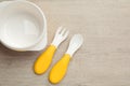 Plastic bowl and cutlery on wooden background, flat lay with space for text. Serving baby food Royalty Free Stock Photo