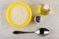 Plastic bowl with dry rice, vegetable oil, salt, metallic spoon