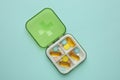 Plastic box with different pills on light blue background, top view Royalty Free Stock Photo