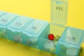 Plastic box with different pills on yellow background, closeup Royalty Free Stock Photo